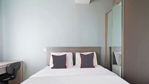 Ein Hotelzimmer mit einem Bett, zwei Kissen, einem Schreibtisch und einem Spiegel.