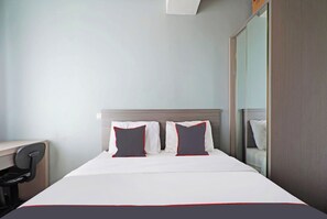 A hotel room with a bed, two pillows, a desk, and a mirror. - Super OYO Collectiono 91566 Easton Park Jatinangor (Cileunyi)
