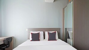 Ein Hotelzimmer mit einem Bett, zwei Kissen, einem Schreibtisch und einem Spiegel.