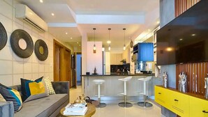 A modern living room with a sofa, a coffee table, and a kitchen area with a bar.