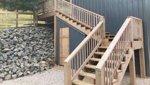 Una escalera de madera conduce a un edificio azul con fachada de metal.