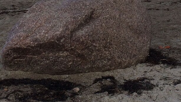 Una pila de piedras sobre una roca grande junto al mar.
