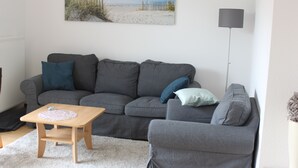 Una sala de estar con un sofá gris, una mesa de centro de madera y una lámpara.