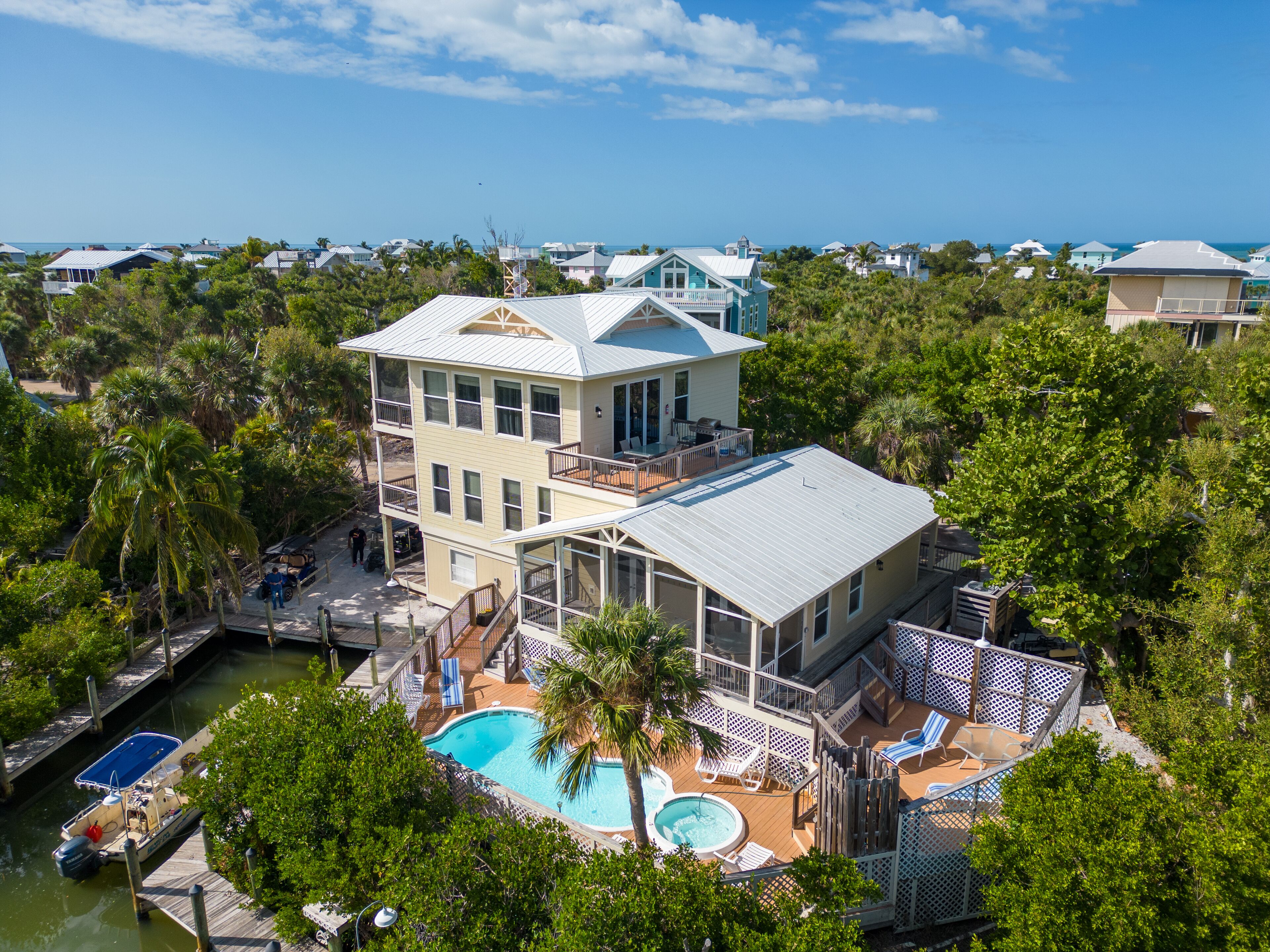 Uma casa de vários andares com uma piscina grande, um píer e vista para o oceano.
