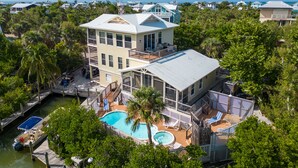 A multi-story house with a large swimming pool, a dock, and a view of the ocean. - Solitude North Captiva, Carts, Dock, Private Pool, Club, Sleeps 12 (Captiva)