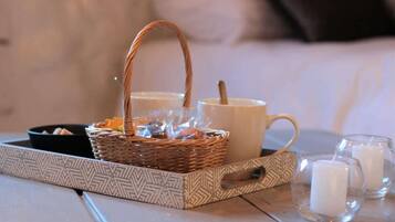 A tray with a wicker basket, a white mug, and two glass candles on a tiled surface.
