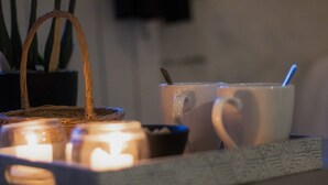 Una bandeja con velas, una cesta y dos tazas sobre una mesa.