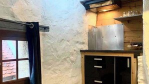 Una cocina compacta con ventana, extractor metálico y un lavamanos pequeño.