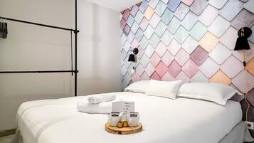 Een hotelkamer met een bed, een handdoek, een dienblad met een koffiekopje en een muur met een geometrisch patroon.