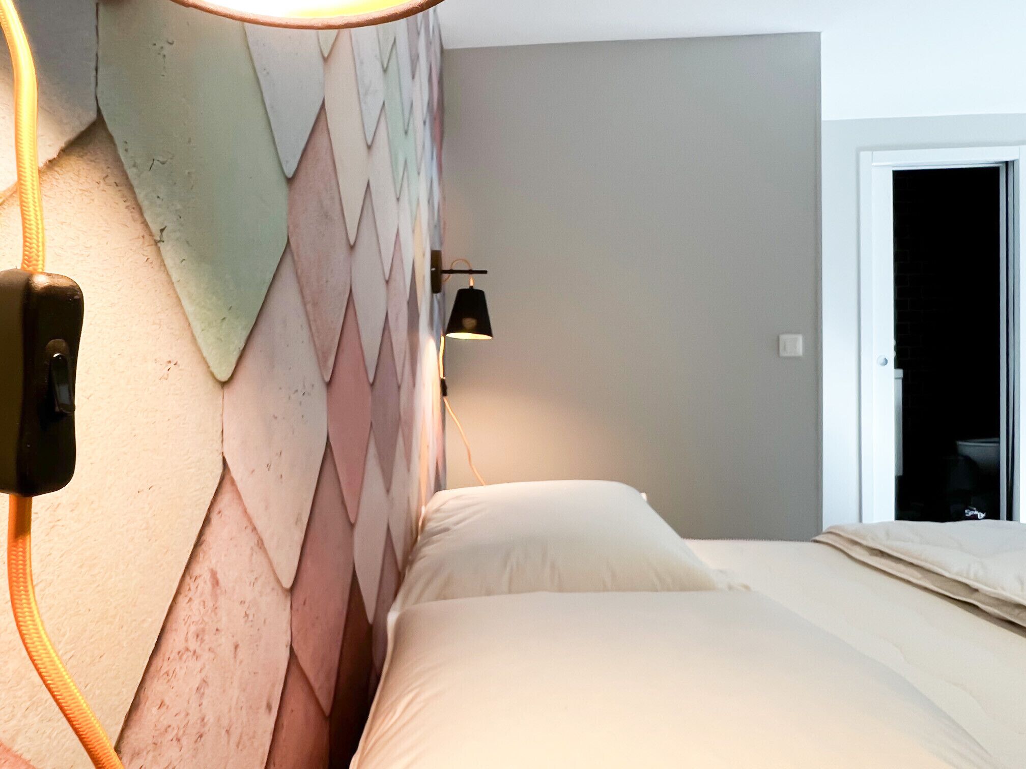A bedroom with a bed, a wall-mounted light, and a door.