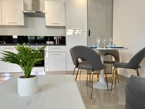 Una cocina moderna con armarios blancos, estufa integrada y comedor con mesa y sillas.