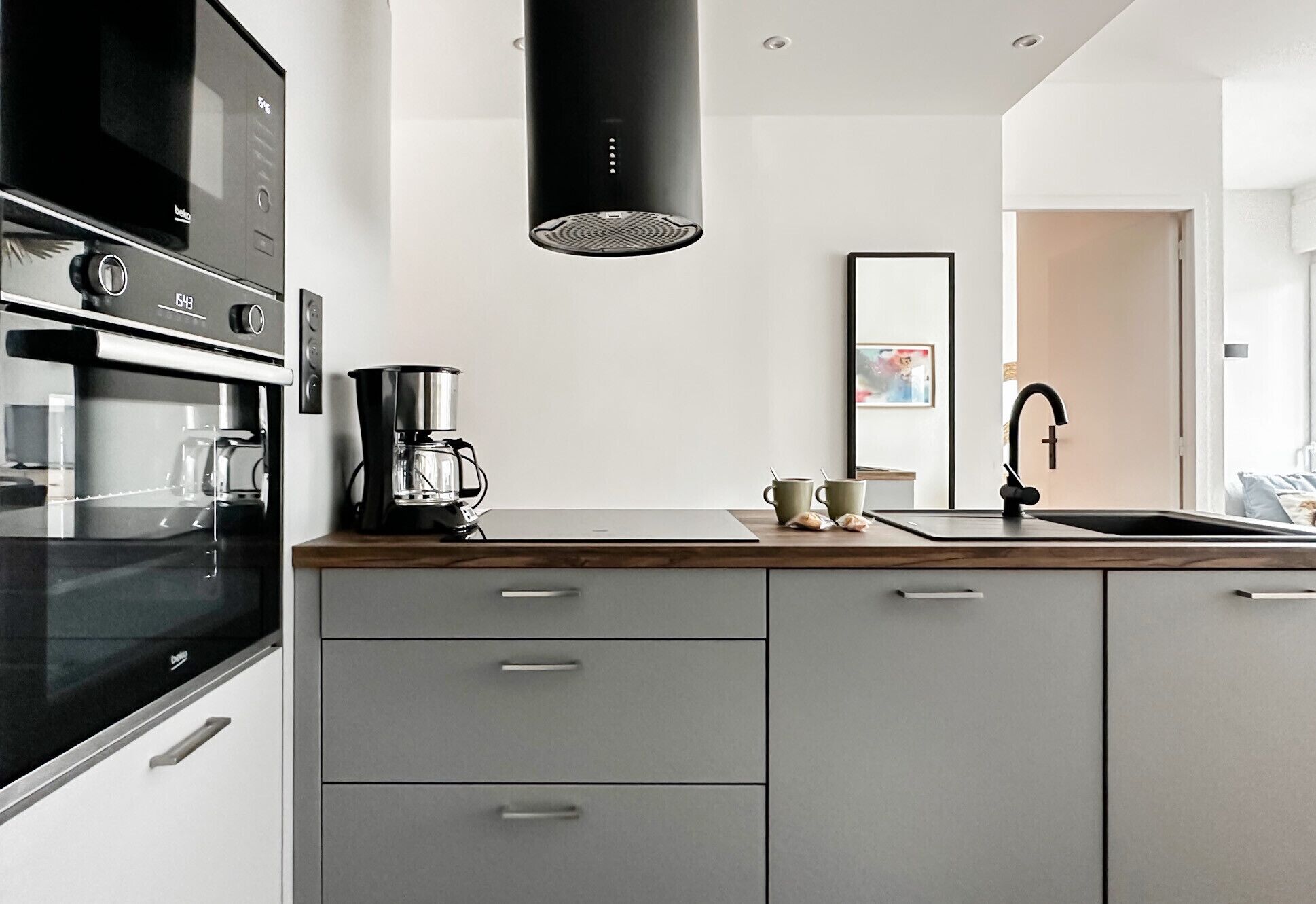 Eine moderne Küche mit eingebautem Ofen, einer Kaffeemaschine und einem Spülbecken mit Armatur.