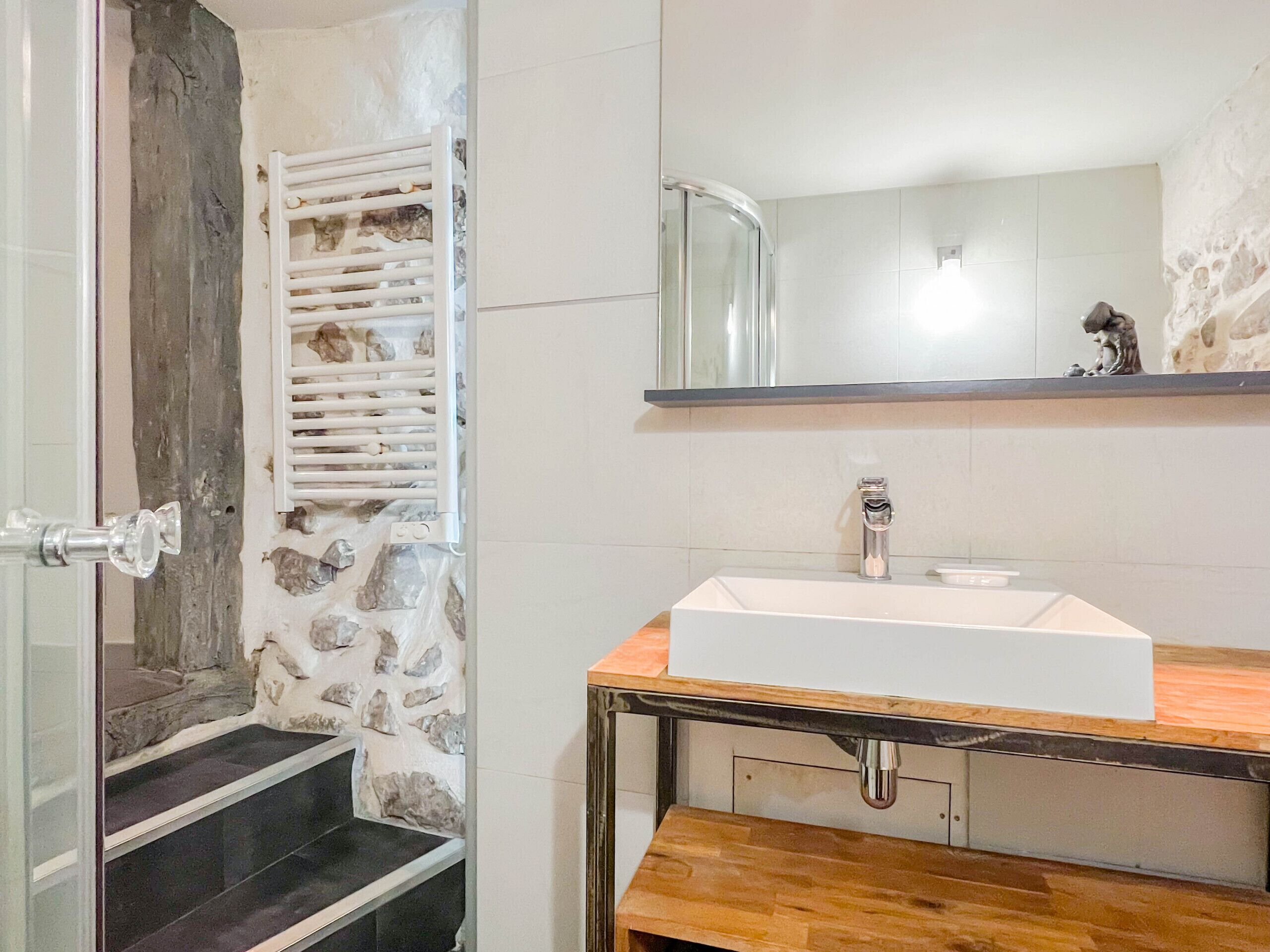 A bathroom with a stone wall, a white sink, and a mirror above it.