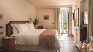 Habitación de hotel con una cama grande, una mesita de noche, un aparador y vistas al exterior.
