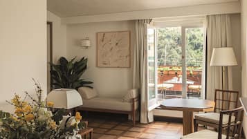 Una sala de estar acogedora con un sofá, una mesa de comedor y sillas. Hay una ventana con cortinas, una planta y un cuadro en la pared.