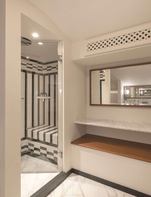 A bathroom with a shower area featuring black and white tiles, a vanity with a mirror and shelves, and a marble countertop. - Splendido Mare, A Belmond Hotel, Portofino (Santa Margherita Ligure)