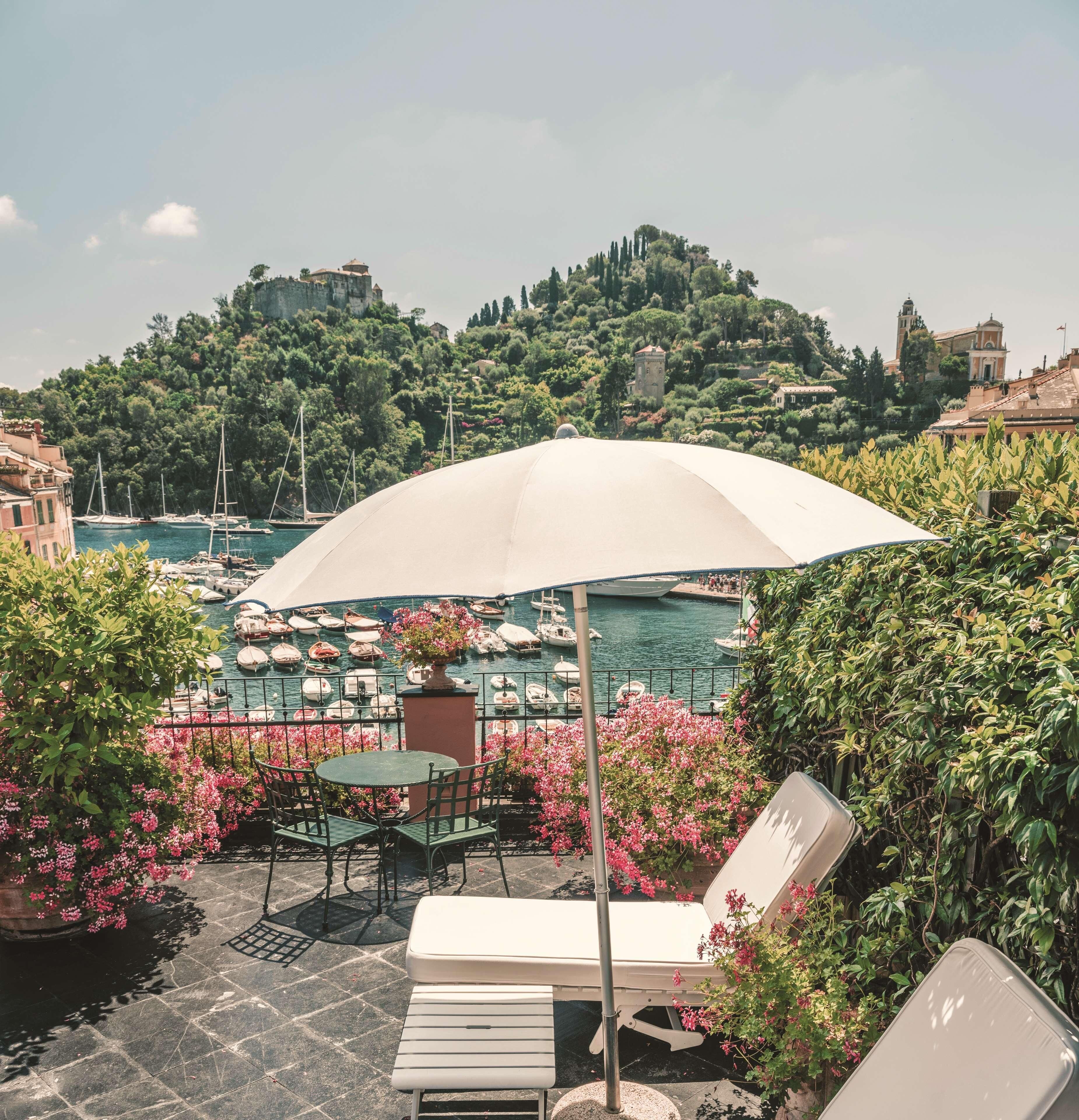A terrace with a table and chairs, a lounge chair, and a large umbrella.