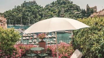 A terrace with a table and chairs, a lounge chair, and a large umbrella.