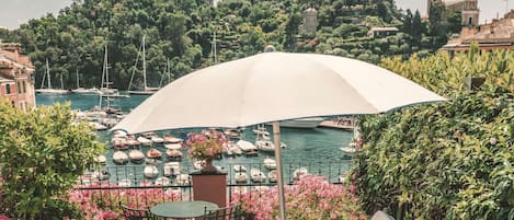 Una terraza con mesa y sillas, un sillón de descanso y un toldo grande.