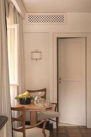 A dining area with a wooden table, chairs, a vase with lemons, and a wall-mounted light fixture. - Splendido Mare, A Belmond Hotel, Portofino (Santa Margherita Ligure)