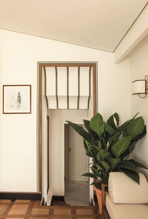 A hallway with a wooden door frame, a large potted plant, and a framed picture on the wall. - Splendido Mare, A Belmond Hotel, Portofino (Santa Margherita Ligure)