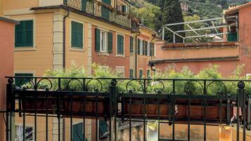A terrace with a table, chairs, and a view of a hillside with buildings.