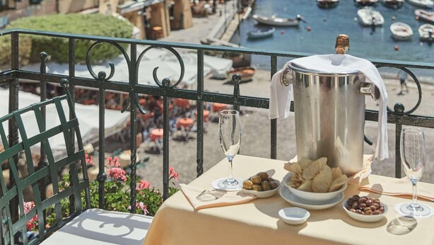 A balcony with a table set for dining, overlooking a marina with boats and colorful buildings. - Splendido Mare, A Belmond Hotel, Portofino (Santa Margherita Ligure)
