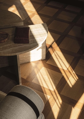 A wooden floor with a geometric pattern, a round table with a dark surface, and a hat on the floor. - Splendido Mare, A Belmond Hotel, Portofino (Santa Margherita Ligure)