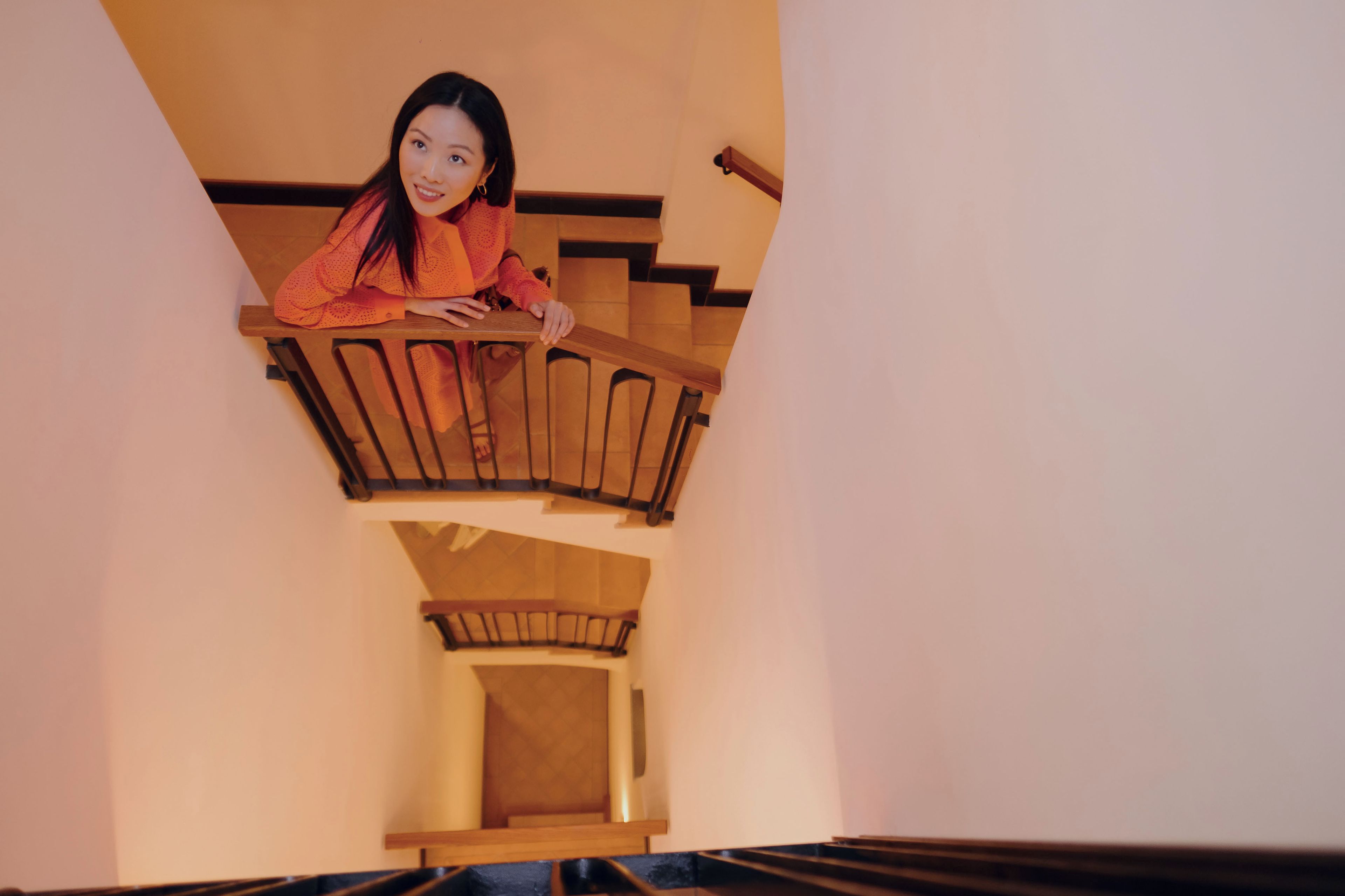 A person standing on a wooden staircase with a view of the interior space below.