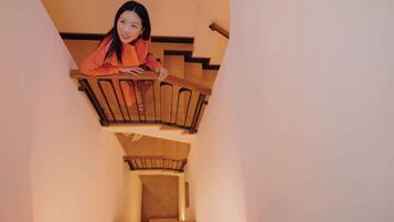 A person standing on a wooden staircase with a view of the interior space below.