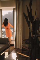 Una donna con un vestito arancione in piedi davanti a una finestra con vista sul mare.