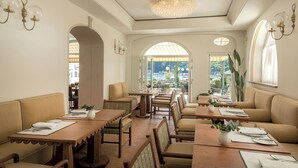 Un restaurante con mesas altas, asientos acolchados, amplias ventanas con vistas y apliques decorativos en la pared.