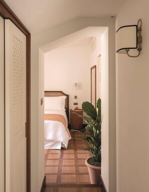 A hotel hallway with a bed, a nightstand, a potted plant, and a wall-mounted light fixture. - Splendido Mare, A Belmond Hotel, Portofino (Santa Margherita Ligure)