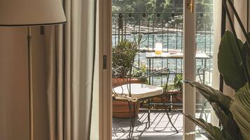 A room with a view of a balcony overlooking a body of water and greenery.