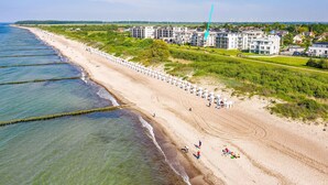 Un hôtel situé sur la côte, avec une longue plage, des éoliennes en arrière-plan et un ciel dégagé.