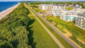 Eine Luftaufnahme einer Küstenwohngegend mit Strand, einer Straße und modernen Wohngebäuden.