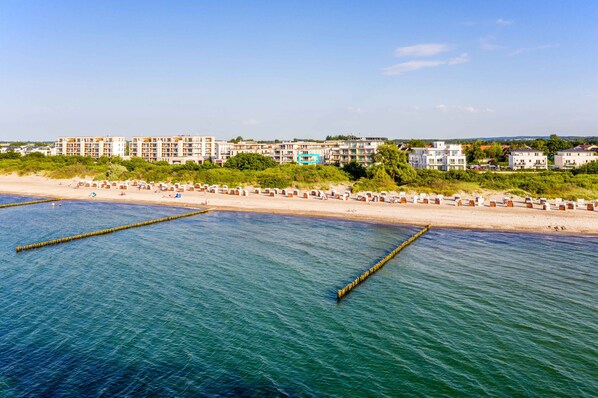 A coastal hotel with multiple buildings, a sandy beach, and a clear blue sea.