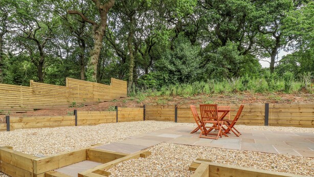 Un jardín con jardineras de madera, un espacio de estar y una valla de madera.