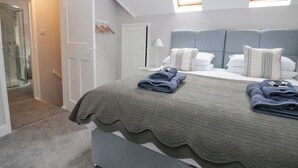 Un dormitorio moderno con una cama grande, cabecera gris y tragaluz.