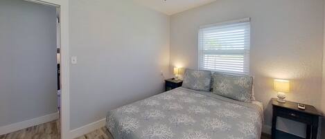 A bedroom with a bed, nightstands, a ceiling fan, and a window with blinds.