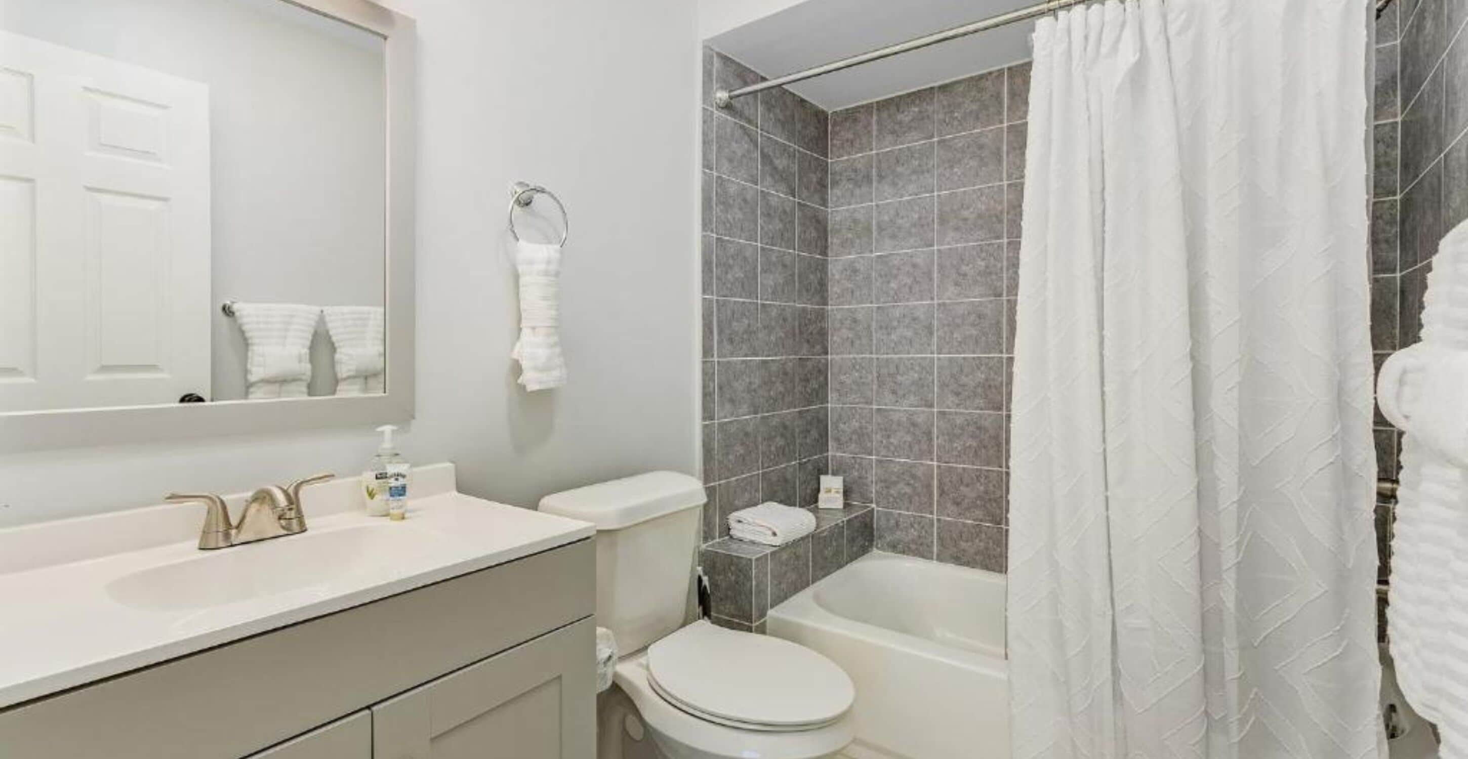 A modern bathroom with a white sink, toilet, and bathtub.