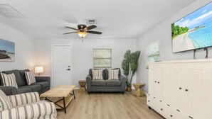 A living room with two sofas, a coffee table, a ceiling fan, a TV, and a cabinet. - Matlacha on Shoreview (Cape Coral)