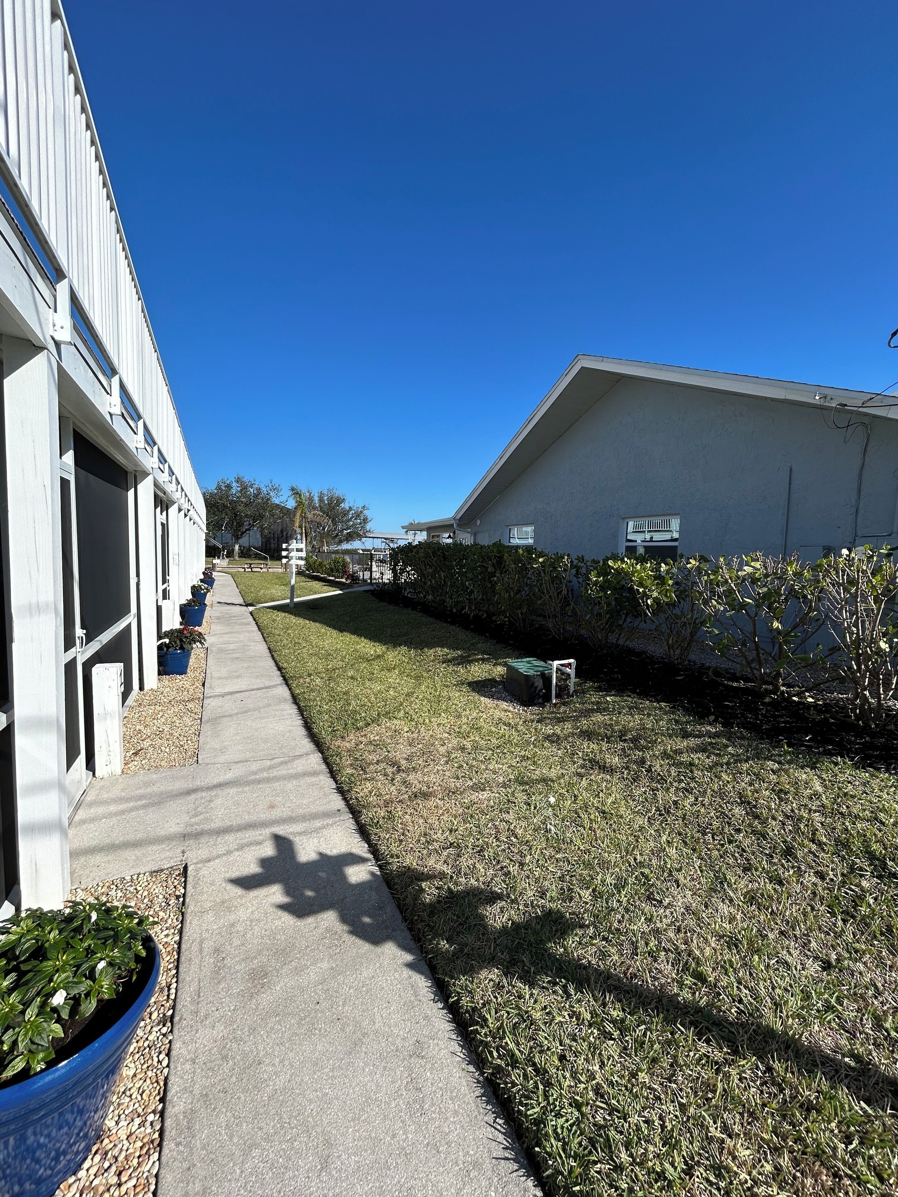 A pathway leading to a building with a flat roof and a large window.