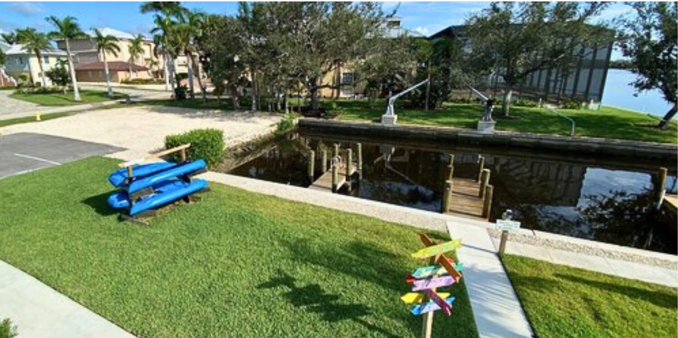 A grassy area with a small pond, a blue bench, and a pinwheel.