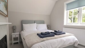 Ein ordentlich eingerichtetes Schlafzimmer mit einem Bett, Nachttischen, einem Fenster mit Blick und einem Bild an der Wand.