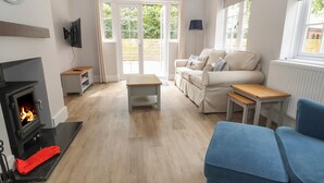 Ein gemütliches Wohnzimmer mit Kamin, einer Couch, einem blauen Sessel und einem Esstisch.