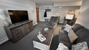 Una sala de estar con una televisión de pantalla plana, un sofá, una mesa de centro y una chimenea.