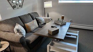Una sala de estar moderna con un sofá modular, una mesa de centro, una lámpara y una mesita auxiliar.