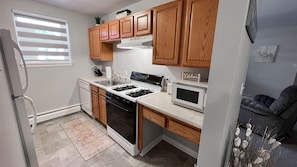 A compact kitchen with wooden cabinets, a stove, a microwave, and a dishwasher.