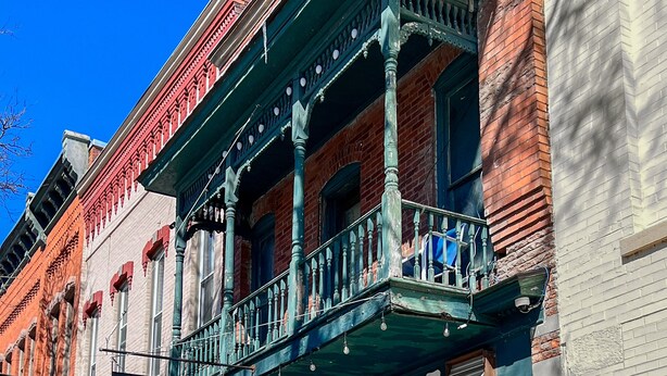 Un edificio histórico con letrero de bar y parrilla, mesas al aire libre y fachada de ladrillo.